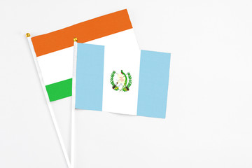 Guatemala and Niger stick flags on white background. High quality fabric, miniature national flag. Peaceful global concept.White floor for copy space.