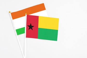 Guinea Bissau and Niger stick flags on white background. High quality fabric, miniature national flag. Peaceful global concept.White floor for copy space.