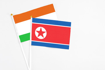 North Korea and Niger stick flags on white background. High quality fabric, miniature national flag. Peaceful global concept.White floor for copy space.
