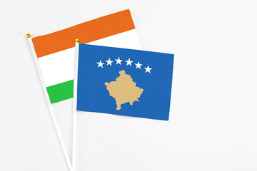 Kosovo and Niger stick flags on white background. High quality fabric, miniature national flag. Peaceful global concept.White floor for copy space.