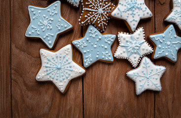 Fototapeta na wymiar Homemade gingersnaps covered with icing on the wooden background; delicious cookies with Christmas shapes