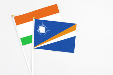 Marshall Islands and Niger stick flags on white background. High quality fabric, miniature national flag. Peaceful global concept.White floor for copy space.