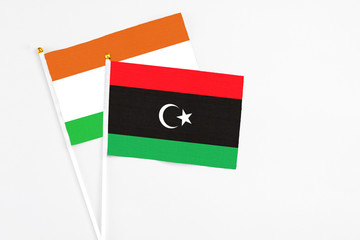 Libya and Niger stick flags on white background. High quality fabric, miniature national flag. Peaceful global concept.White floor for copy space.