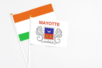 Mayotte and Niger stick flags on white background. High quality fabric, miniature national flag. Peaceful global concept.White floor for copy space.