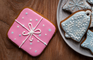 Homemade gingersnaps covered with icing on the wooden background; delicious cookies with Christmas shapes