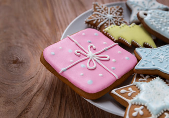 Homemade gingersnaps covered with icing on the wooden background; delicious cookies with Christmas shapes