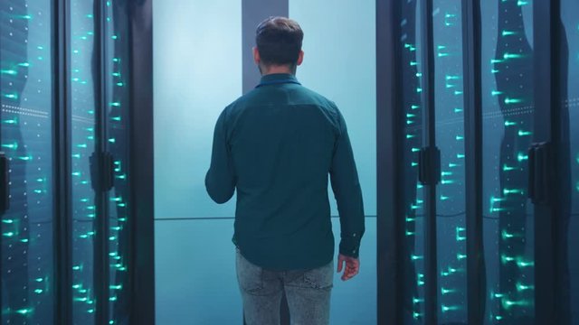 IT technician walking in futuristic database server corridor inspecting supercomputer network webhosting in big data center.