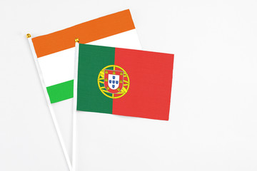 Portugal and Niger stick flags on white background. High quality fabric, miniature national flag. Peaceful global concept.White floor for copy space.