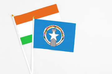 Northern Mariana Islands and Niger stick flags on white background. High quality fabric, miniature national flag. Peaceful global concept.White floor for copy space.