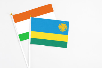Rwanda and Niger stick flags on white background. High quality fabric, miniature national flag. Peaceful global concept.White floor for copy space.