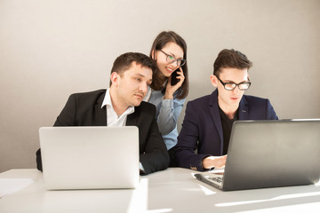 Young male and female business partners sitting behind a computer monitor. Focused business team working, woman talking on mobile phone