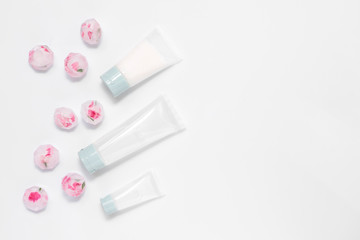 Recipe of youth, face care treatment, cream transparent tubes, ice cubes with herbs and flowers isolated on white background. Flat lay, top view, copy space. Beauty therapy products concept