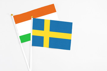 Sweden and Niger stick flags on white background. High quality fabric, miniature national flag. Peaceful global concept.White floor for copy space.