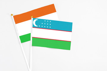 Uzbekistan and Niger stick flags on white background. High quality fabric, miniature national flag. Peaceful global concept.White floor for copy space.