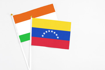 Venezuela and Niger stick flags on white background. High quality fabric, miniature national flag. Peaceful global concept.White floor for copy space.