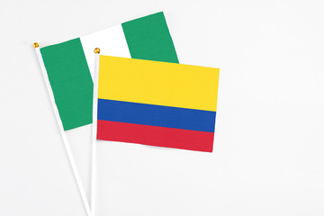 Colombia and Nigeria stick flags on white background. High quality fabric, miniature national flag. Peaceful global concept.White floor for copy space.