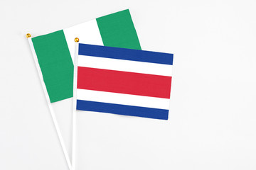 Costa Rica and Nigeria stick flags on white background. High quality fabric, miniature national flag. Peaceful global concept.White floor for copy space.