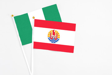 French Polynesia and Nigeria stick flags on white background. High quality fabric, miniature national flag. Peaceful global concept.White floor for copy space.