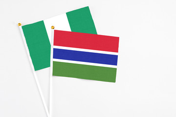Gambia and Nigeria stick flags on white background. High quality fabric, miniature national flag. Peaceful global concept.White floor for copy space.