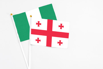 Georgia and Nigeria stick flags on white background. High quality fabric, miniature national flag. Peaceful global concept.White floor for copy space.