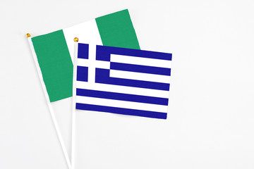 Greece and Nigeria stick flags on white background. High quality fabric, miniature national flag. Peaceful global concept.White floor for copy space.