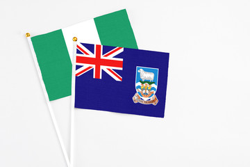 Fototapeta premium Falkland Islands and Nigeria stick flags on white background. High quality fabric, miniature national flag. Peaceful global concept.White floor for copy space.
