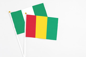 Guinea and Nigeria stick flags on white background. High quality fabric, miniature national flag. Peaceful global concept.White floor for copy space.
