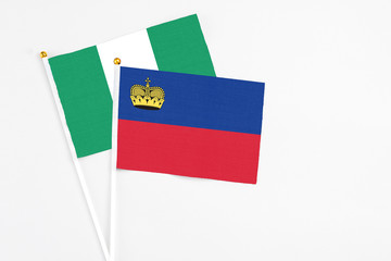 Liechtenstein and Nigeria stick flags on white background. High quality fabric, miniature national flag. Peaceful global concept.White floor for copy space.