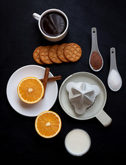 HEALTHY BREAKFAST WITH ORANGE, CINNAMON,MILK AND SQUEEZER ON BLACK BACKGROUND