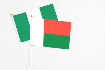 Madagascar and Nigeria stick flags on white background. High quality fabric, miniature national flag. Peaceful global concept.White floor for copy space.