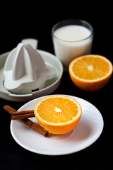 HEALTHY BREAKFAST WITH ORANGE, CINNAMON,MILK AND SQUEEZER ON BLACK BACKGROUND