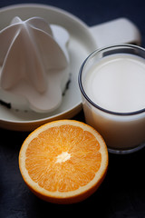 ORANGE CUTED TOGETHER WITH SQUEEZER AND GLASS OF MILK. HEALTHY BREAKFAST