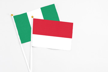 Monaco and Nigeria stick flags on white background. High quality fabric, miniature national flag. Peaceful global concept.White floor for copy space.