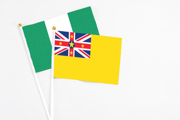 Niue and Nigeria stick flags on white background. High quality fabric, miniature national flag. Peaceful global concept.White floor for copy space.