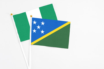 Solomon Islands and Nigeria stick flags on white background. High quality fabric, miniature national flag. Peaceful global concept.White floor for copy space.