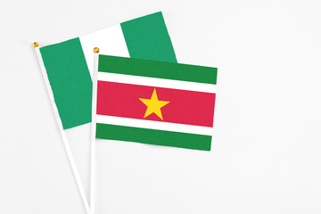 Suriname and Nigeria stick flags on white background. High quality fabric, miniature national flag. Peaceful global concept.White floor for copy space.