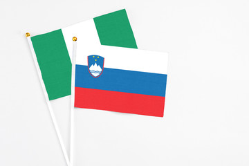 Slovenia and Nigeria stick flags on white background. High quality fabric, miniature national flag. Peaceful global concept.White floor for copy space.