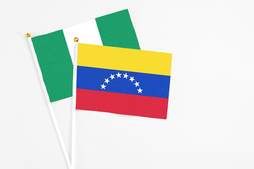 Venezuela and Nigeria stick flags on white background. High quality fabric, miniature national flag. Peaceful global concept.White floor for copy space.