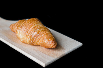 Fresh chocolate croissant on a wooden plate