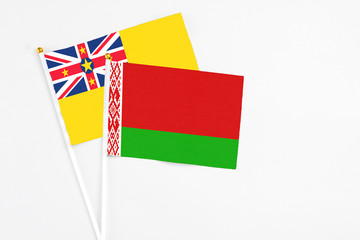 Belarus and Niue stick flags on white background. High quality fabric, miniature national flag. Peaceful global concept.White floor for copy space.