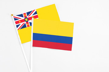 Colombia and Niue stick flags on white background. High quality fabric, miniature national flag. Peaceful global concept.White floor for copy space.