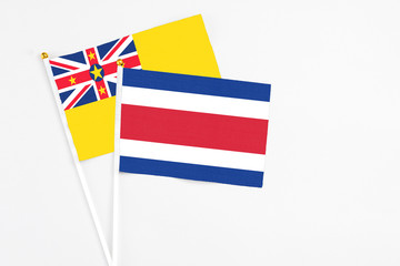 Costa Rica and Niue stick flags on white background. High quality fabric, miniature national flag. Peaceful global concept.White floor for copy space.