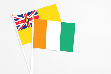 Cote D'Ivoire and Niue stick flags on white background. High quality fabric, miniature national flag. Peaceful global concept.White floor for copy space.