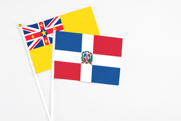 Dominican Republic and Niue stick flags on white background. High quality fabric, miniature national flag. Peaceful global concept.White floor for copy space.