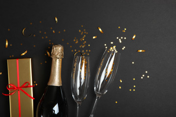 champagne, confetti, gifts and glasses on a colored background top view. Concept holiday, christmas, new year, birthday, valentines day. Celebrate, give. Place for text.