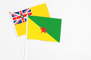 French Guiana and Niue stick flags on white background. High quality fabric, miniature national flag. Peaceful global concept.White floor for copy space.