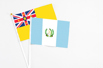 Guatemala and Niue stick flags on white background. High quality fabric, miniature national flag. Peaceful global concept.White floor for copy space.