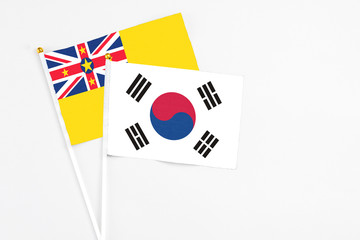 South Korea and Niue stick flags on white background. High quality fabric, miniature national flag. Peaceful global concept.White floor for copy space.