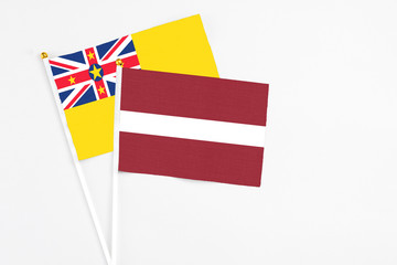 Latvia and Niue stick flags on white background. High quality fabric, miniature national flag. Peaceful global concept.White floor for copy space.