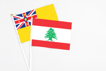 Lebanon and Niue stick flags on white background. High quality fabric, miniature national flag. Peaceful global concept.White floor for copy space.